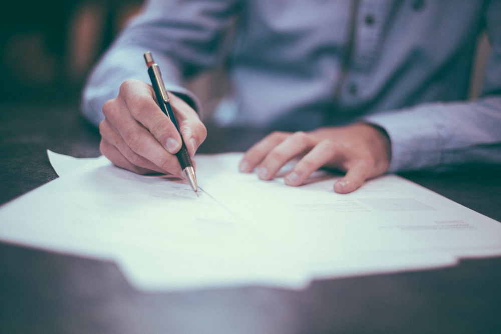 A business owner signing documents, representing the use of retirement funds to finance a business.